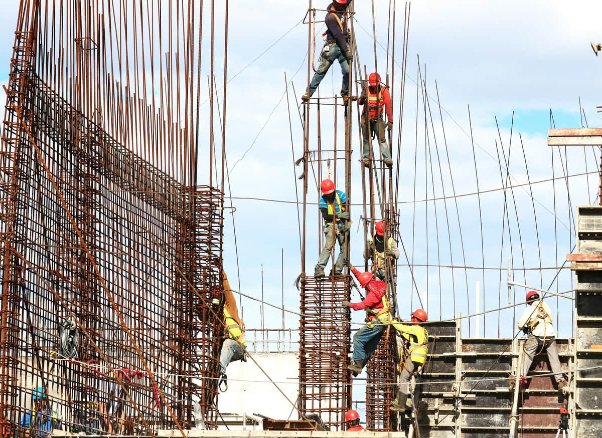 Beton sütunlar üçün armatur karkası bağlayan işçilər